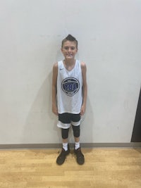 a young boy in a basketball uniform standing in front of a wall