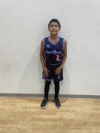 a young boy in a basketball uniform standing in front of a wall