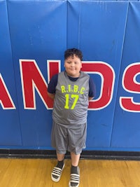 a young boy standing in front of a basketball court