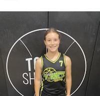 a young girl in a basketball uniform standing in front of a wall