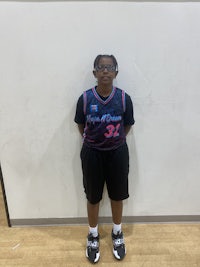 a girl in a basketball uniform standing in front of a wall