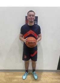 a young man holding a basketball in front of a wall