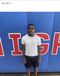 a young man standing in front of a high school wall