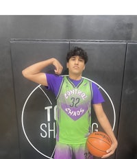 a young man posing with a basketball in front of a wall