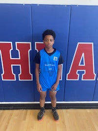 a young boy in a blue uniform standing in front of a wall