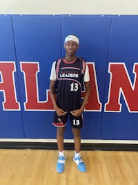 a young man in a basketball uniform standing in front of a wall