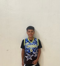 a young boy in a basketball uniform standing in front of a wall