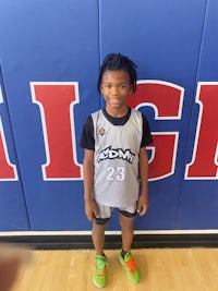 a young boy standing in front of a basketball court