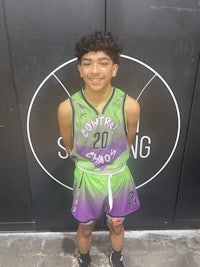 a young boy in a basketball uniform standing in front of a wall