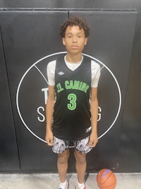 a young boy in a basketball uniform standing next to a basketball