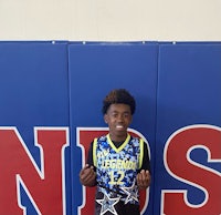 a young boy is standing in front of a basketball court