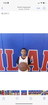 a young man holding a basketball in front of a wall