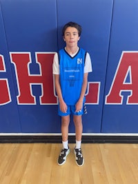 a young boy standing in front of a basketball court