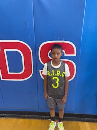 a young boy standing in front of a basketball court
