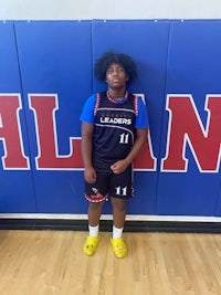 a young man in a basketball uniform standing in front of a wall