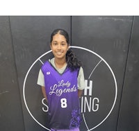 a young girl in a purple and purple basketball uniform standing in front of a wall