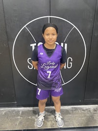 a girl in a purple uniform standing in front of a basketball court