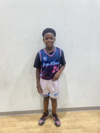 a young boy in a basketball uniform posing for a picture