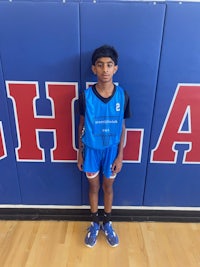 a young boy standing in front of a basketball court