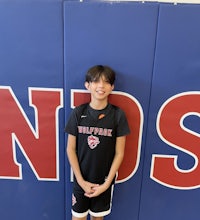a young boy in a basketball uniform standing in front of a wall