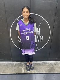 a girl in a purple uniform standing in front of a basketball court