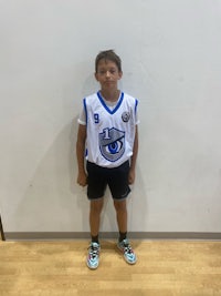 a young boy in a basketball uniform standing in front of a wall