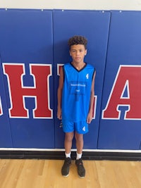 a young boy standing in front of a basketball court