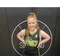 a girl in a basketball uniform standing in front of a wall