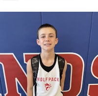 a boy in a basketball uniform standing in front of a wall