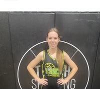 a girl in a basketball uniform standing in front of a wall