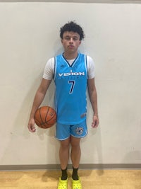 a young man holding a basketball in front of a wall
