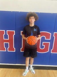 a young man holding a basketball in front of a wall