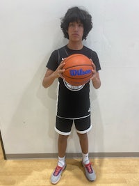 a young man holding a basketball in front of a wall