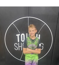 a young boy standing in front of a basketball court