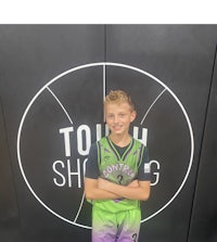 a young boy standing in front of a basketball court