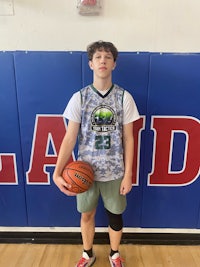a young man holding a basketball in front of a wall