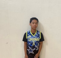 a young boy in a basketball uniform standing in front of a wall