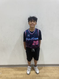 a boy in a basketball uniform standing in front of a wall