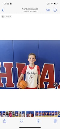 a boy is holding a basketball in front of a wall