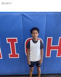 a young boy standing in front of a high school wall