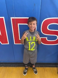 a young boy standing in front of a basketball court