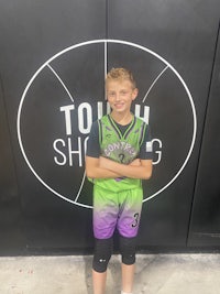 a young boy posing in front of a basketball court