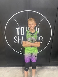 a young boy posing in front of a basketball court