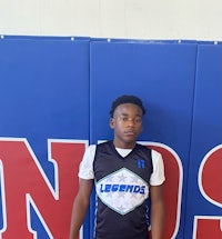 a young boy in a basketball uniform standing in front of a wall