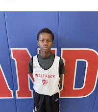 a young boy in a basketball uniform standing in front of a wall