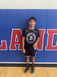 a young man standing in front of a basketball court