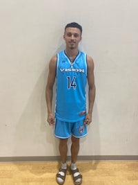 a young man in a blue basketball uniform standing in front of a wall