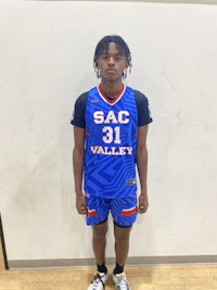a young man in a basketball uniform standing in front of a wall