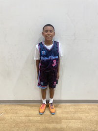 a young boy in a basketball uniform posing for a picture