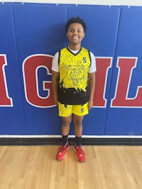 a young boy standing in front of a basketball court